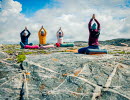 A group of people practicing yoga outdoors on the coast.