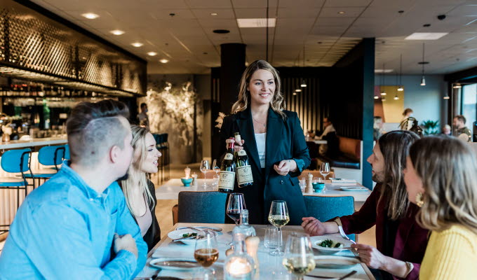 Leende servitris serverar vin vid bordet