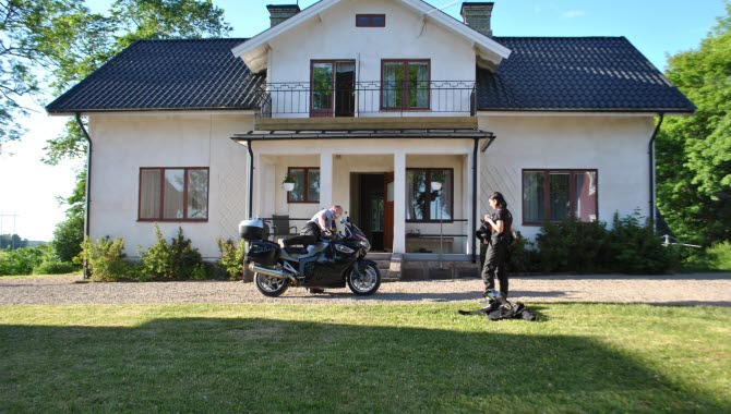 2 personer som står utanför Berglunda vandrarhem med en motorcykel.