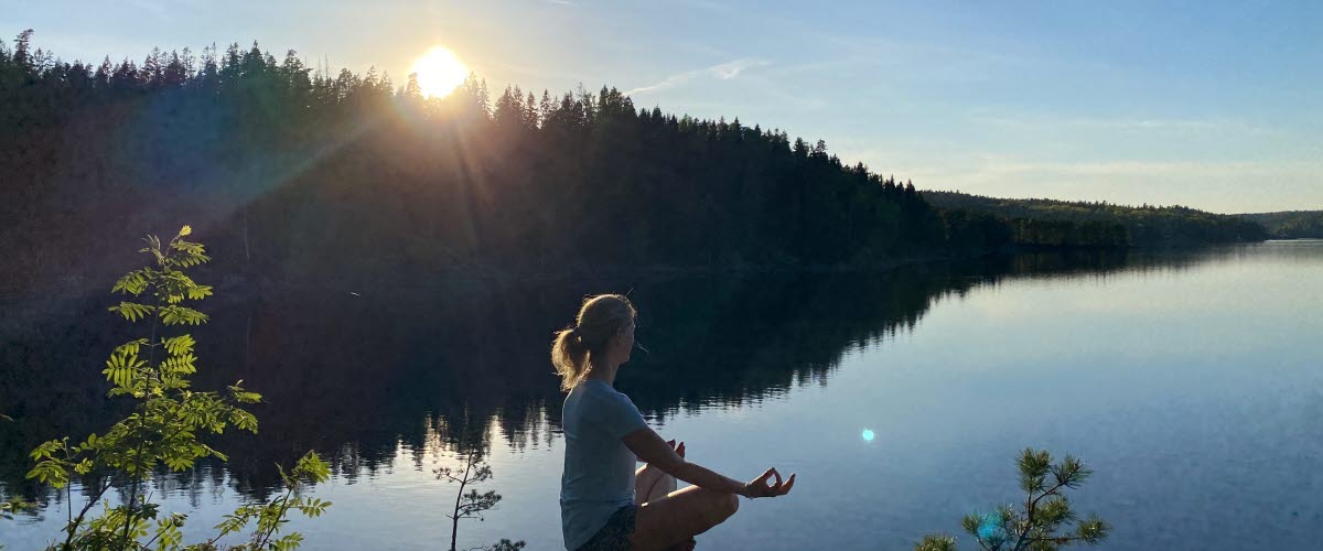 Person som utför yoga vid en sjö