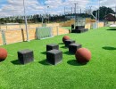 Green artificial grass with black squares on stools and red balls.