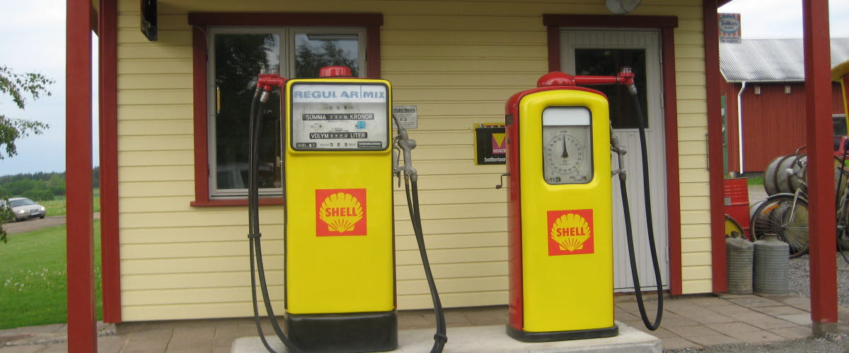 An old shellmack with two yellow gasoline pumps in front.
