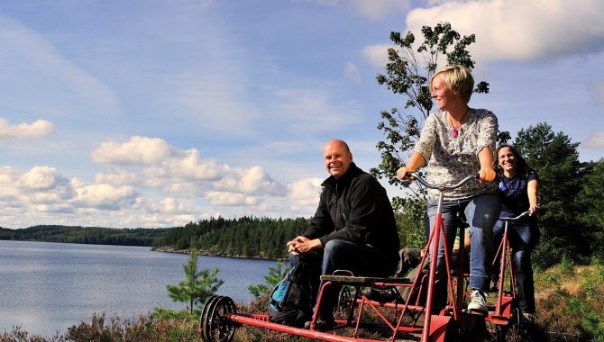 Three people riding a rail bike along a lake.