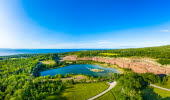 The old limestone quarry filled with clear blue water. The quarry is surrounded by green nature.