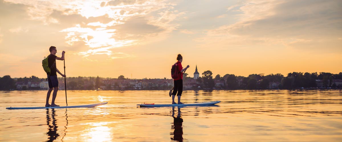 Two people are slowly paddling on a Stand up paddleboard on lake Vättern. 