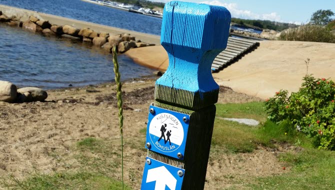 Vandringsled Kuststigen, markör på stolpe vid havet.