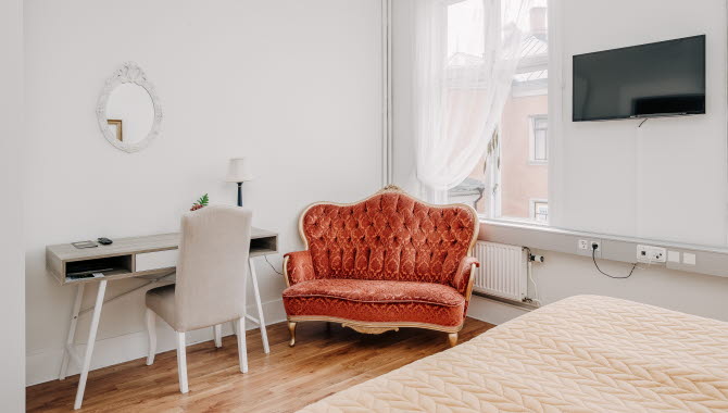 En säng, skrivbord och en orange soffa i gammal stil.