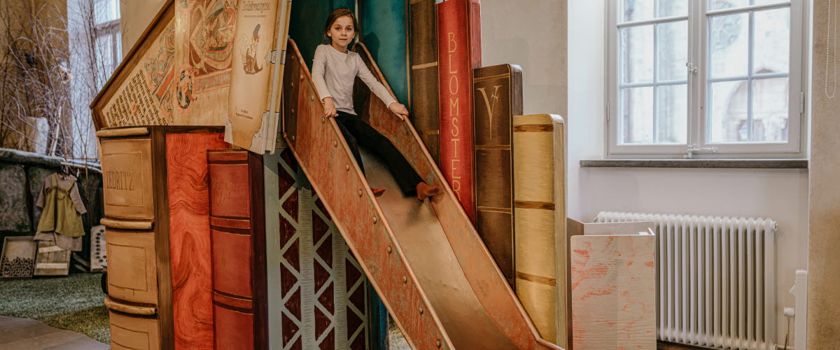 Bokaventyret. A child go down the slide.