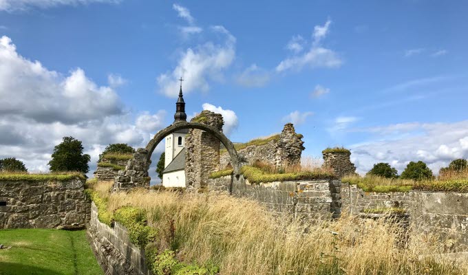 Klosterruinen i förgrunden och Gudhems kyrka i bakgrunden.