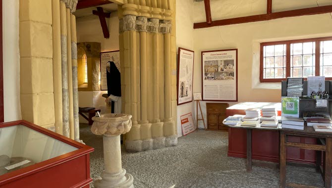 Interiörbild från museet. Ett bokbord och stenpelare.