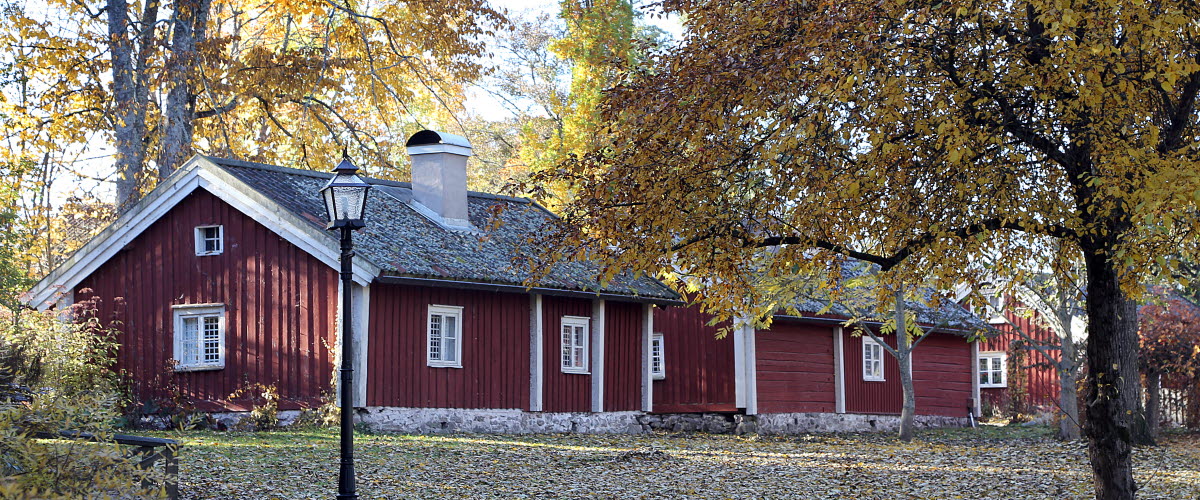 Två röda små trähus med vita knutar på Turbinhusön i Tidaholm i höstskrud.
