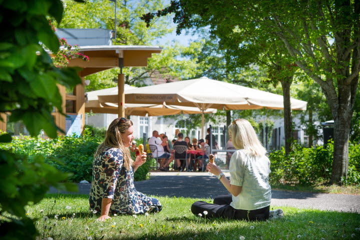 Två kvinnor sitter i en park och äter glass
