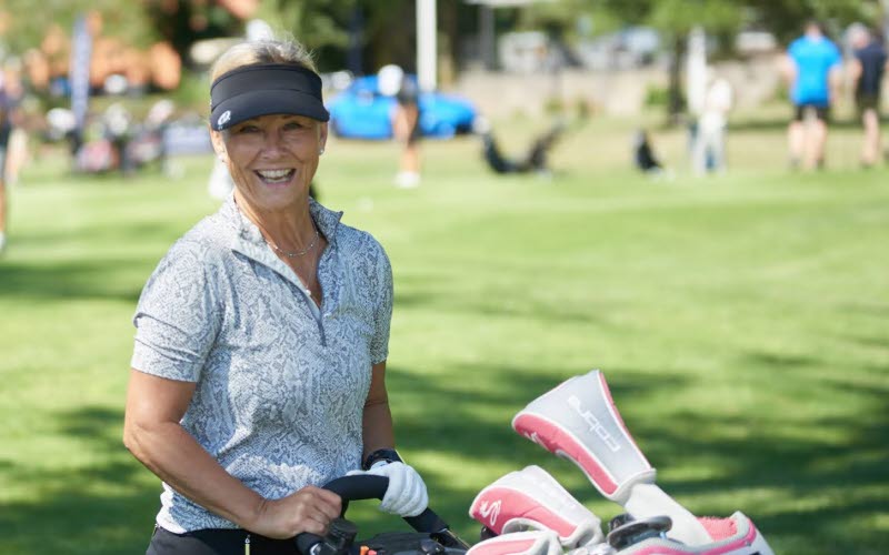 En tjej med golfvagn som tittar mot kameran