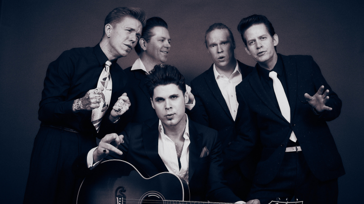 En svart-vit bild på fem män var av en håller i en gitarr
