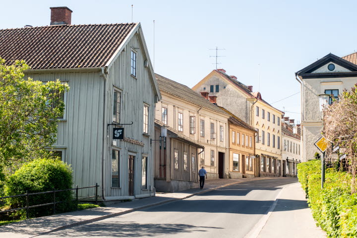 En tom gata med en person som går, gamla hus runt omkring i trä