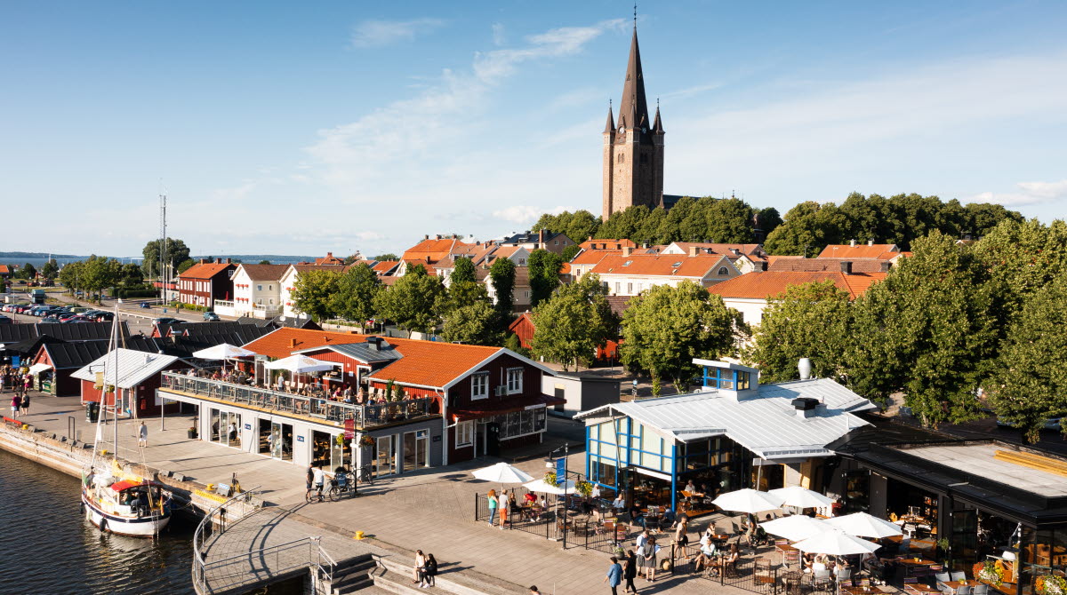 Flygfoto över Mariestads gästhamn med restauranger och bodar. I bakgrunden syns delar av Gamla Stan och Mariestads domkyrka.
