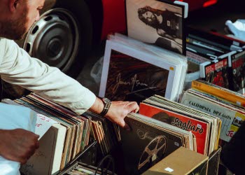 En närbild på en man som bläddrar bland massa gamla LP-skivor i en låda på golvet.