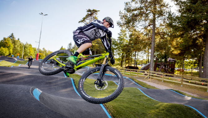 En man hoppar i luften med sin gröna cykel i Billingens Bikepark