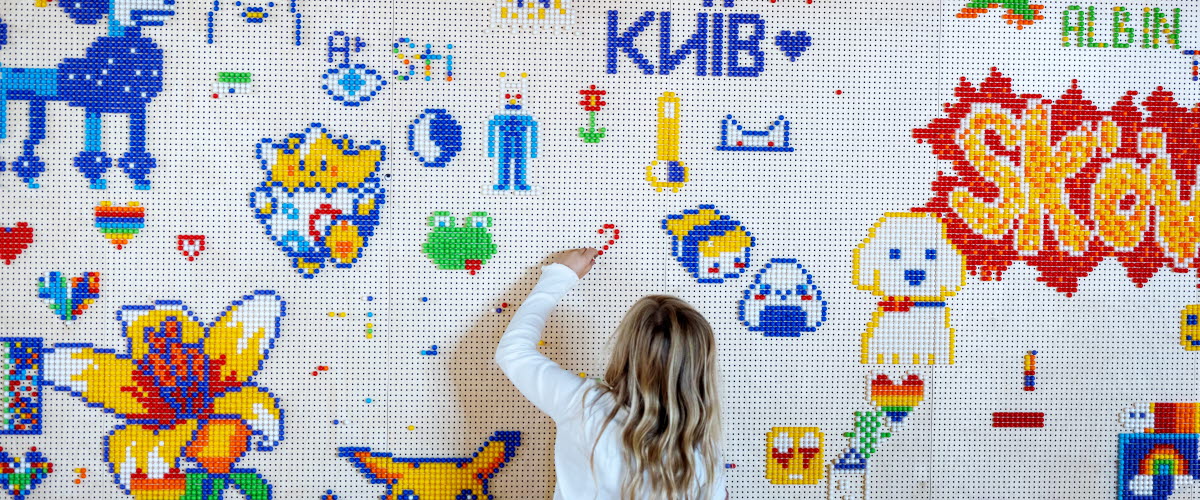 Ett barn står och ritar på en vägg som har flera målningar på sig sedan tidigare