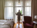 Woman in bathrobe standing in the doorway to the balcony of the hotel room.