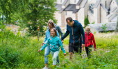 En familj ute i naturen, i bakgrunden en klosterkyrka.