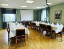 Inside a restaurant. Green walls, white tablecloths on long tables.