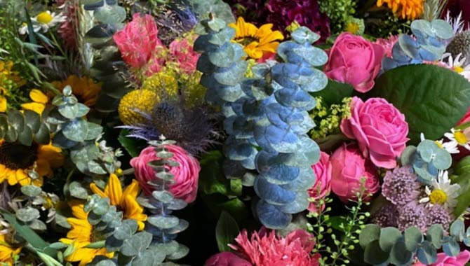 Närbild på en bukett med blommor i gult, rosa och grönt.