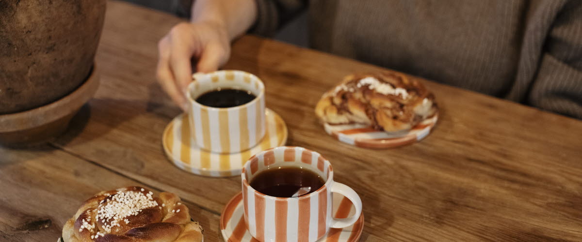 Two striped coffee cups and two buns.