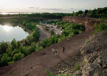 Tre människor promenerar vid Stora Stenbrottet, Kinnekulle med utsikt över Vänern