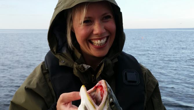 Woman on a fishing tour on lake Vättern, haveing caught a pike.
