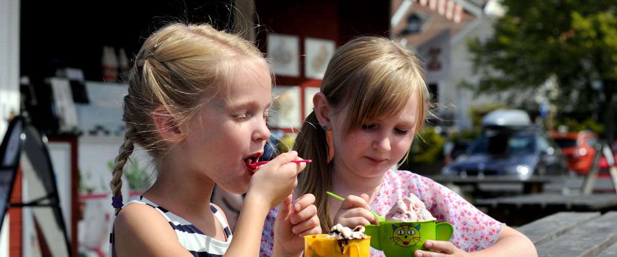 Barn äter glass vid bodarna i Mariestads gästhamn. En av de röda bodarna syns i bakgrunden.