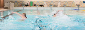 Two swimming indoors in swimming pool.