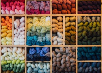 En bild på en butikshylla som är fullproppad med garnnystan i olika glada färger.