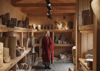 En kvinna i röd kappa står inne i ett stenmuseum.