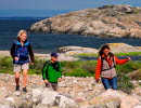 Three people are hiking across a cobblestone field at North Koster.