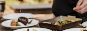 Four white plates on which you can see hands placing food.