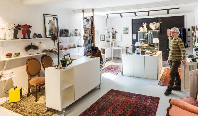 En bild inifrån en butik med hantverksföremål. Tak, väggar, golv och möbler går i vitt och gör att de orientaliska mattorna på golvet poppar - liksom alla varor som står uppradade på hyllor.