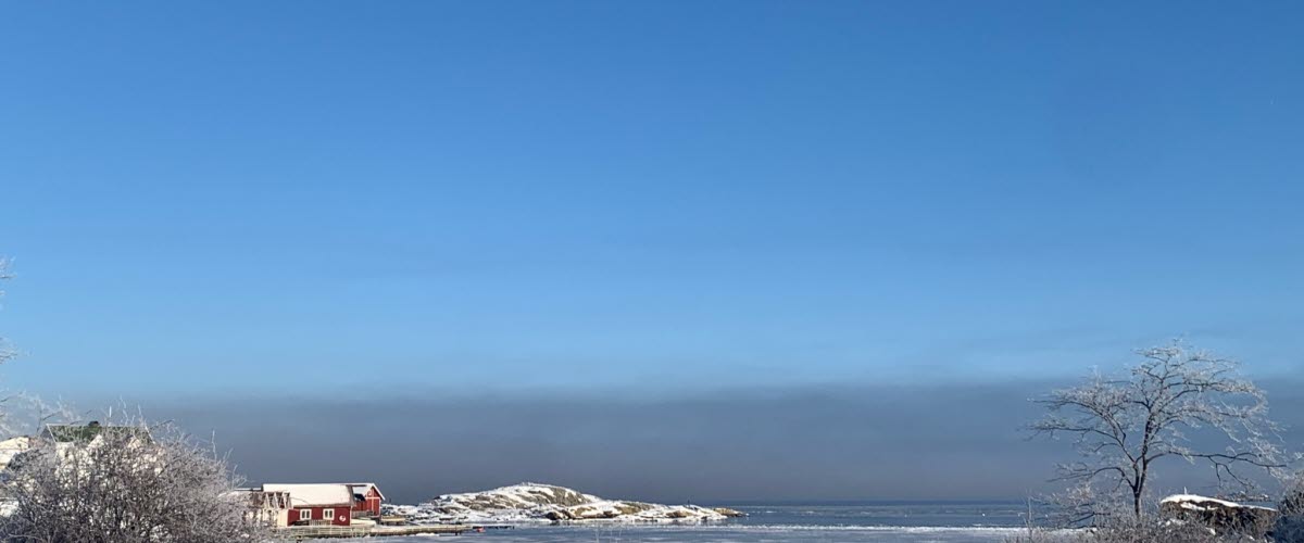 Winter landscap with snow looking out over the sea with some small red fishing houses on Skaftö island, Lysekil