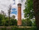 Lookout tower in red brick with trees and bushes all around.