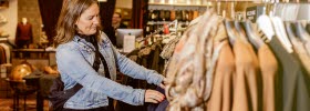 Woman peeking at clothes in a store.