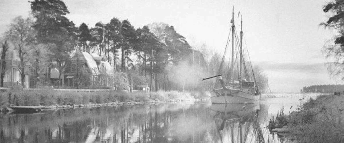 Black and white archive image of the Göta Canal in Karlsborg, with a boat sailing on the water.