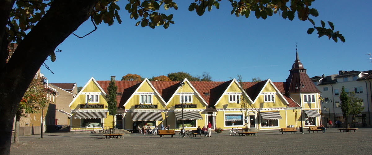 Basarlängan på Gamla Torget i Tidaholm. Huset är en gammal gul träbyggnad med flera affärsverksamheter i.