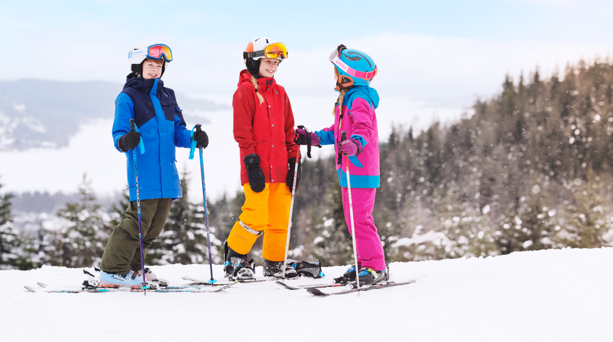 Barn och vuxna i färgglada kläder i slalombackarna i Ulricehamn
