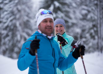 A girl and guy dressed in cross-country ski equipment checking into the camera.