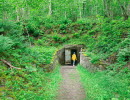 A person i a yellow jacket passing through the entrance to the millstone mine.