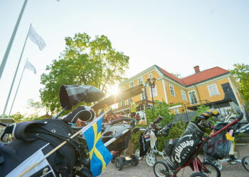 Golfutrustning och en herrgårdsbyggnad i motljus