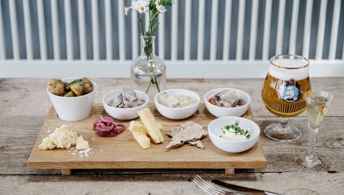 A wooden tray with pickled herring, a cold beer and snaps at Bryggcafét i Bovallstrand.