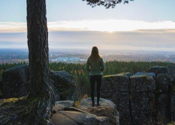 Kvinna som står med ryggen mot kameran och kikar ut över en vacker utsikt.