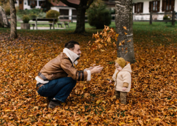 Far och barn som leker bland höstlov