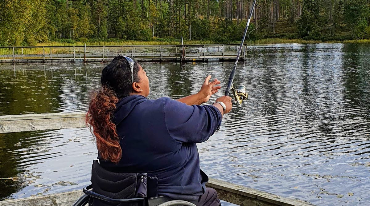 Kvinna som sitter i rullstol och fiskar vid Björnsjön på Hökensås.